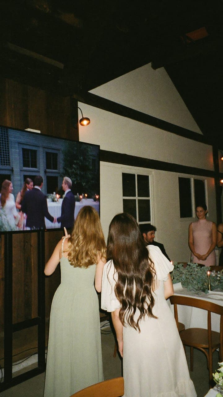 Gasten kijken naar het grote scherm, waar net een foto van de avond voorbijkomt
