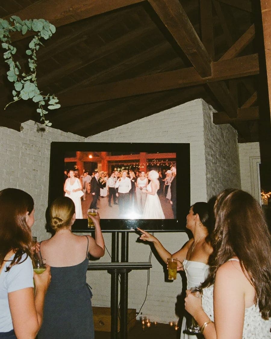 Gasten wijzen naar het grote scherm in de zaal, waar hun foto's live voorbijkomen